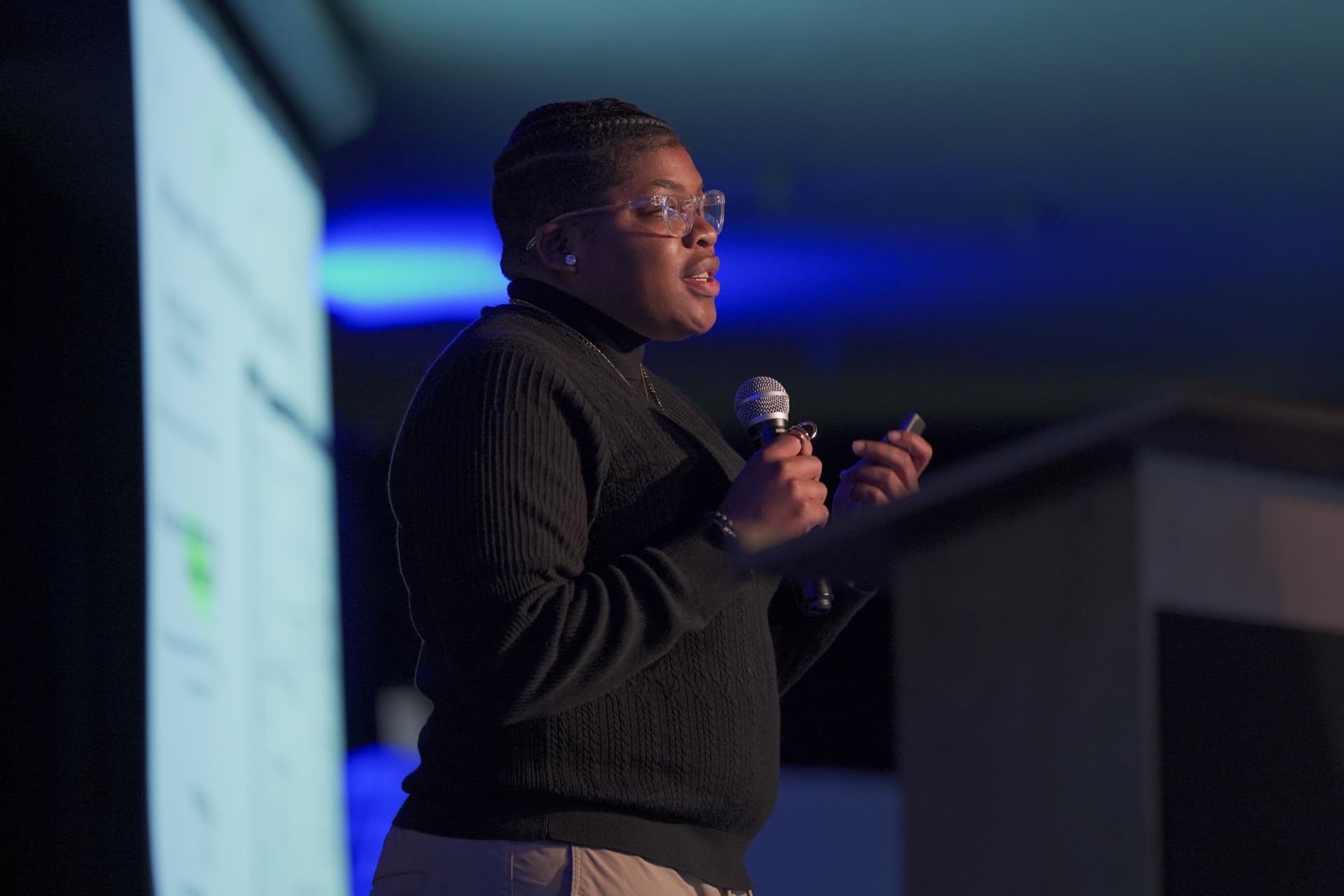 Jannae Gammage presenting on stage with a microphone